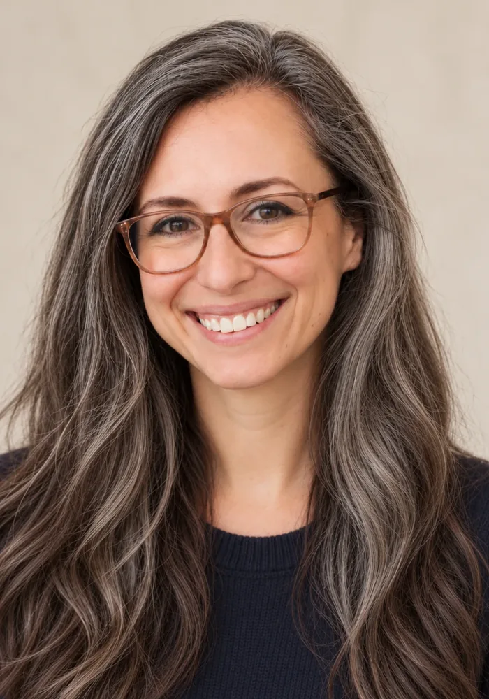 Erin Ankeny, smiling, wearing tortoiseshell glasses and a navy sweater